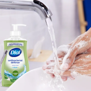 Someone washing their hands under running water, with a bottle of Dial Antibacterial Defense in the background