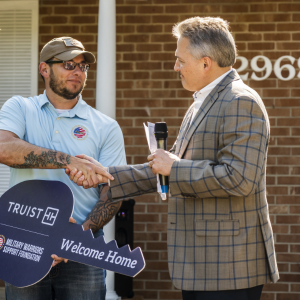 Sgt. David Long shaking another person's hand and receiving a large key