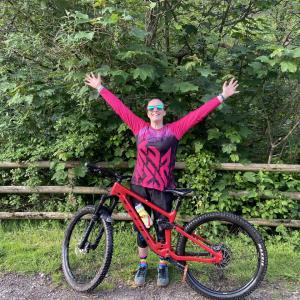 A person with raised arms behind a bicycle.