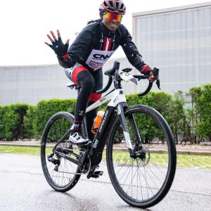 A person riding a bike, waving.