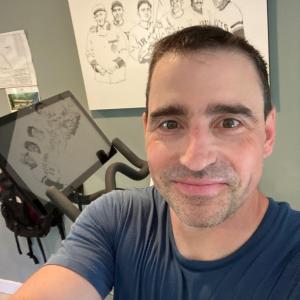 A person smiling next to an indoor bike. 