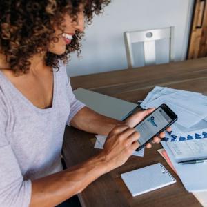 Person using their phone at a table spread with papers