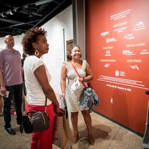 People attending a museum opening, viewing exhibits.