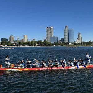 A group in a long boat paddling on a body of water.