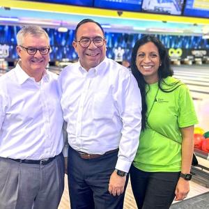 Three people posed together in a bowling alley.