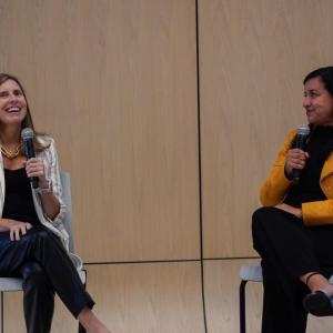 Two seated people speaking with microphones.