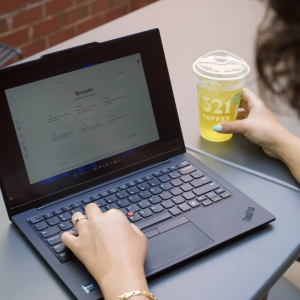 Someone using a laptop while holding a beverage