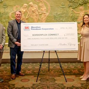 Three people standing next to an oversized check