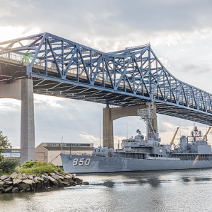 a large bridge over a water way and boat underneath