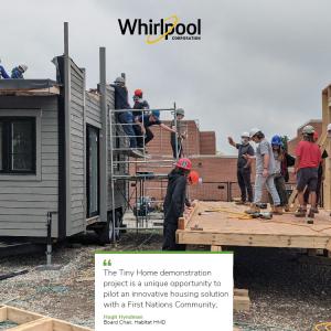 a group of people stand on wood building structure next to a completed tiny house