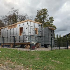a tiny home being built, insulation exposed, scaffolding outside