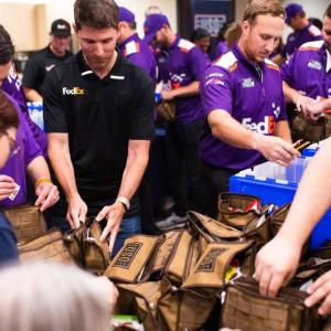 FedEx volunteers assemble crates of care packages
