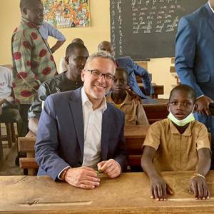 adult sitting next to a child at a school desk in a school room