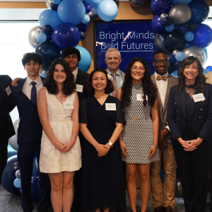 People smiling and standing together under blue balloons