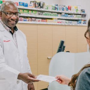 Calvin Bryant, pharmacist, handing something to a customer.