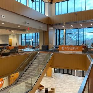 A stairwell of a multi story building "Campbell University" banner on a handrail.