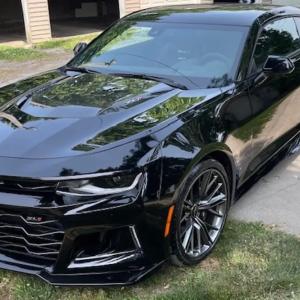 A black car parked in a grassy area
