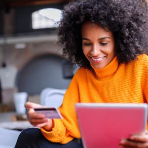 a person holding a credit card in one hand and a tablet in the other