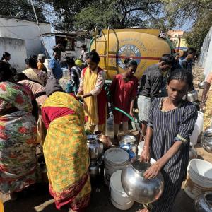 People gathered, collecting water in jugs.