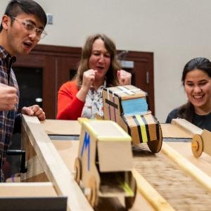 People racing small cars made out of cardboard 