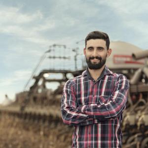 A person standing in front of a tractor in a field