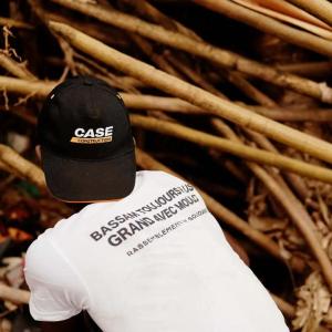 A person wearing a white t-shirt and a black cap, knelt down on the ground