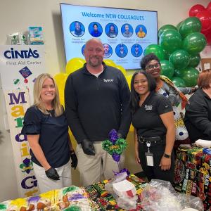 People standing together behind a table of food at an event