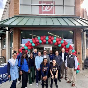 A group of people posed outside a Walgreens. A balloon arch over the entrance.