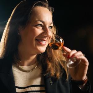 Agathe Boinot smiling, smelling a small glass of cognac.