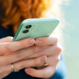 A person using a cellular device with both hands.