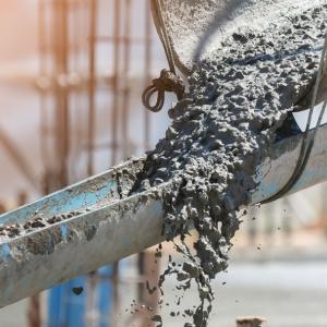 Concrete flowing down troughs at a construction site.