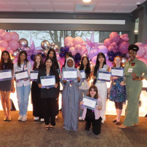 A group holding awards in front of balloons