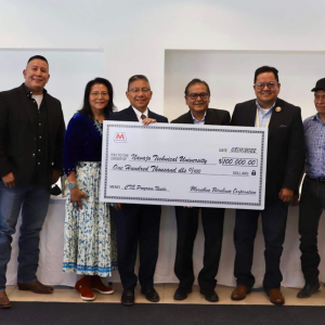a group of people standing, three holding a large check 