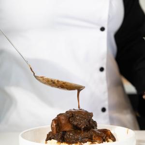 Close up of sauce being poured on a dish.