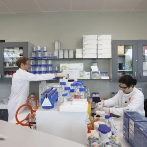 Two people in a laboratory setting wearing protective gear.