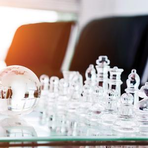 Clear chess set and a small clear globe on a table.