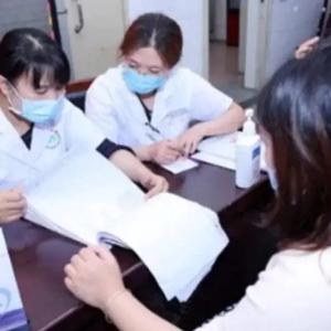 two medical professionals flipping through a stack of papers, others seated on the other side of the table