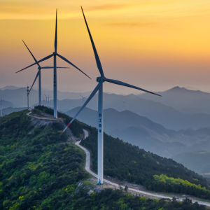 Wind turbines on top of a peak, setting sun in the background