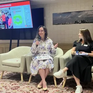 Two women sitting an talking to a crowd