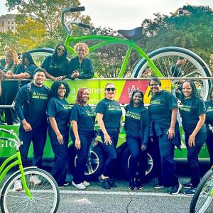 Volunteers posed in front of a float with a giant green bike. Other, normal sized, green bikes in front of them.