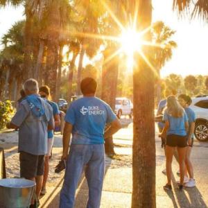 A group of volunteers gathered on a sidewalk in a park setting.