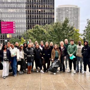 S group posed together outside. Some holding black trash bags.