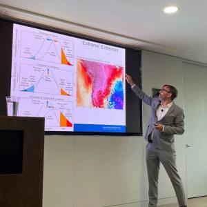 speaker gesturing to a brightly colored climate change graph