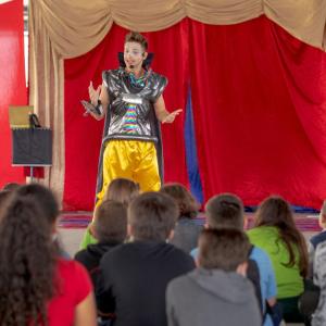 A person in costume performing for an audience of children.