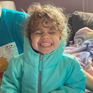 A smiling child in a teal coat