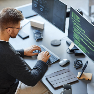 A person using a desktop computer with multiple screens.