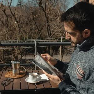 Ruggero Rollini reading outside with a cup of coffee