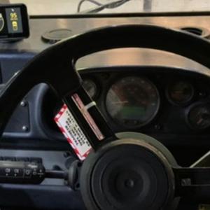 Inside of a heavy machinery vehicle, a warning label and monitor on the dashboard.