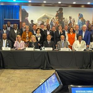 all committee members, some seated at a long table, some standing behind them.