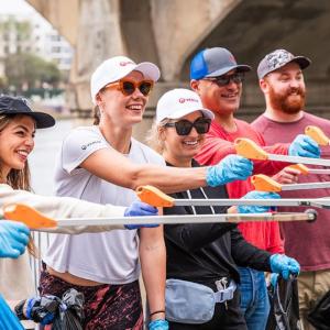 Smiling volunteers posed together extending litter pickers.